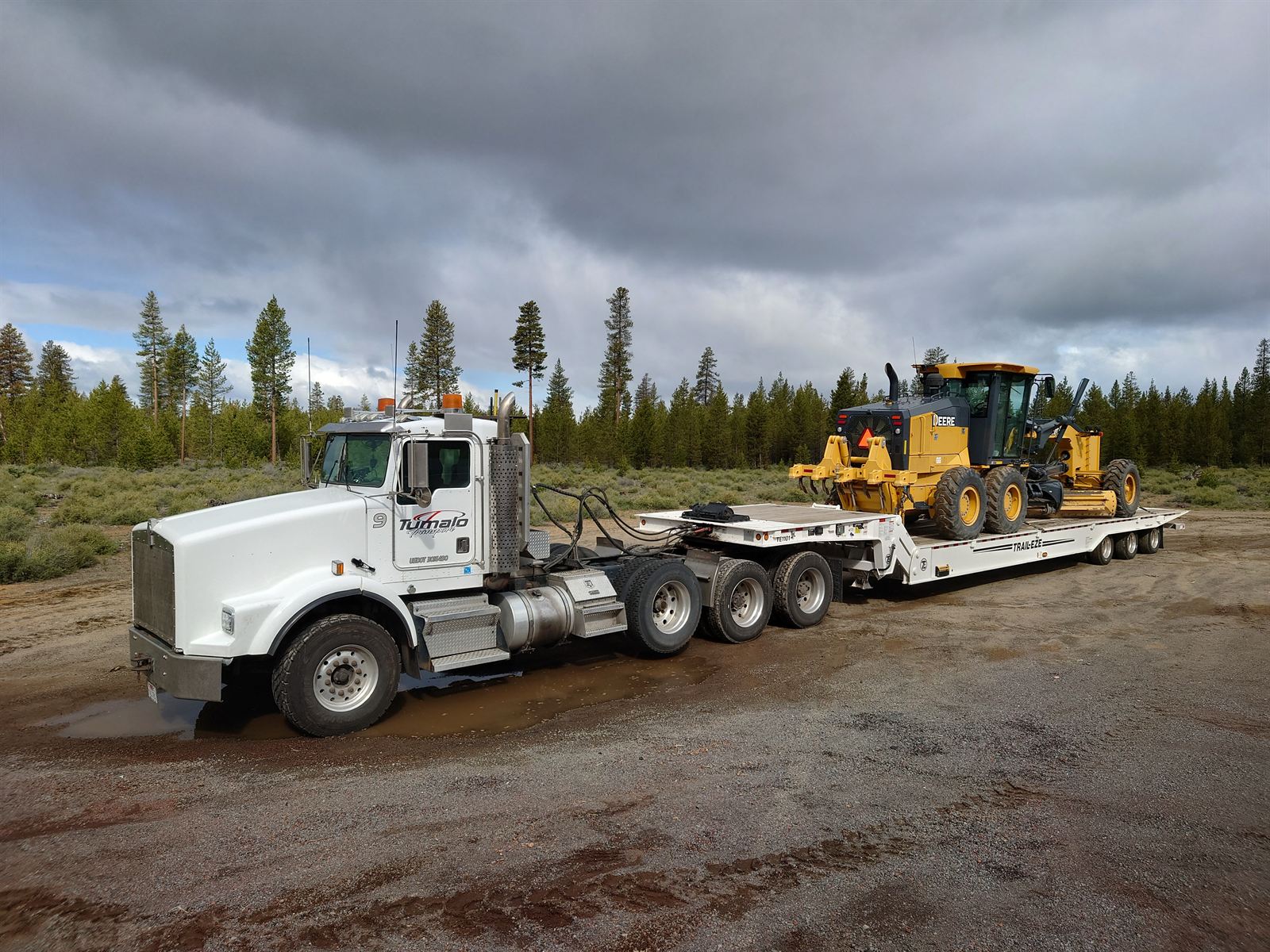 Tumalo Transport Kenworth and Trail-Eze lowboy loaded with a John Deere motor grader in the Central Oregon pines
