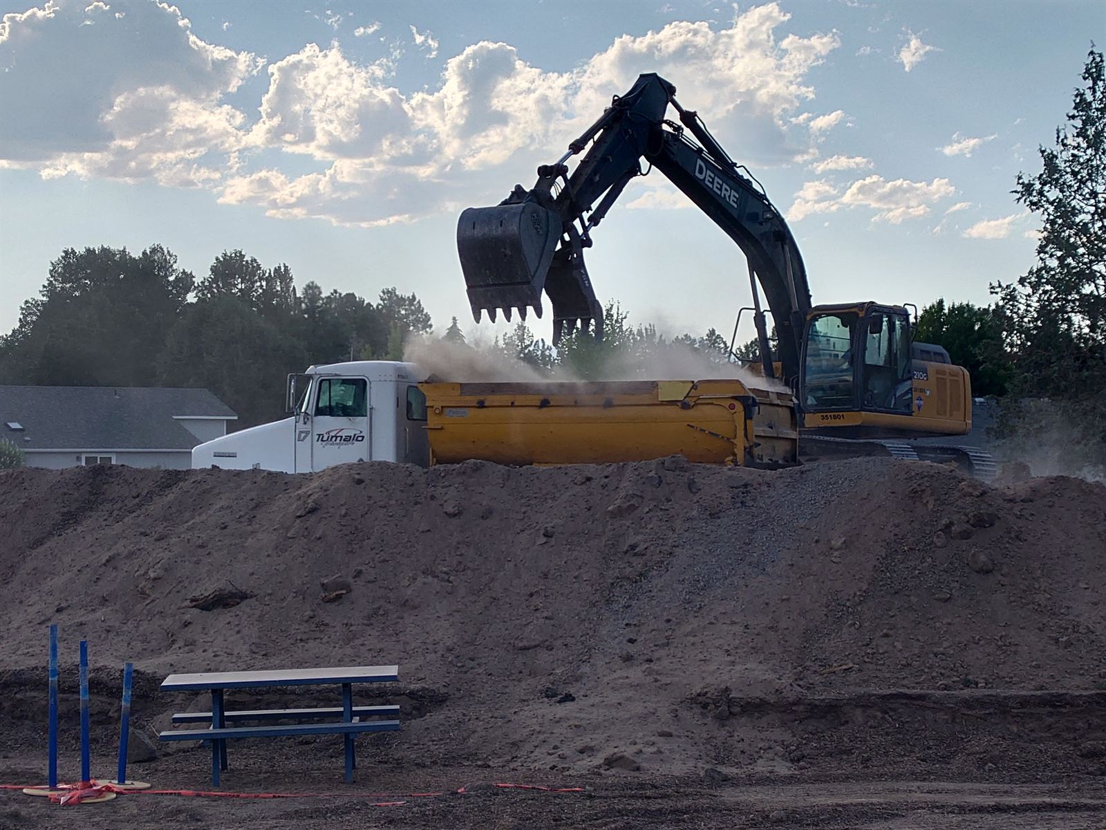 Excavator loading a Tumalo Transport dump truck with dirt on a Bend job site