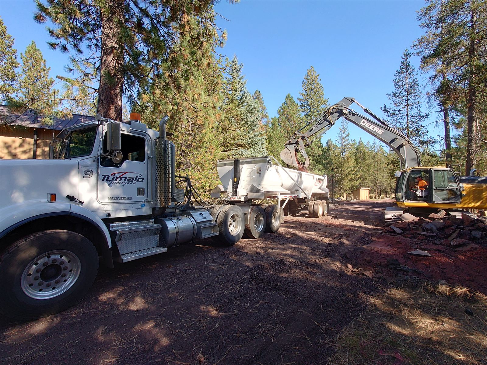 Tumalo Transport truck and side-dump trailer working a job site in the ponderosa pines