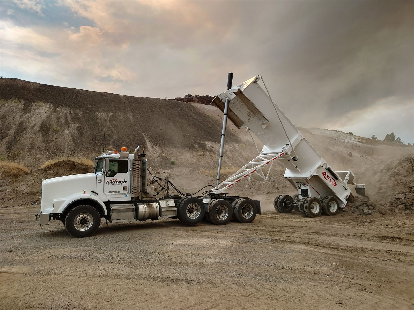 Tumalo Transport truck and transfer trailer dumping rock at a Central Oregon quarry