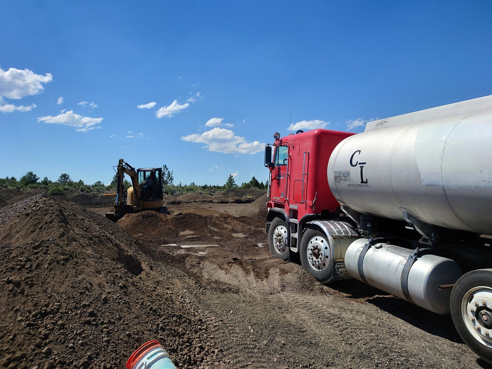 Tumalo Transport water truck on a Central Oregon job site alongside an excavator